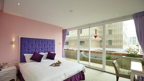 A modern hotel room with a large bed, a balcony with a view of the city, and a small table with a chair. - Lion King Hotel (Kaohsiung)
