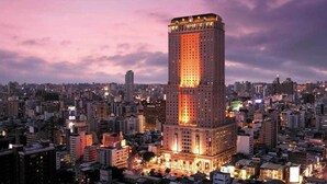 A high-rise building with a prominent central tower, surrounded by a dense urban environment at dusk. - Lion King Hotel (Kaohsiung)