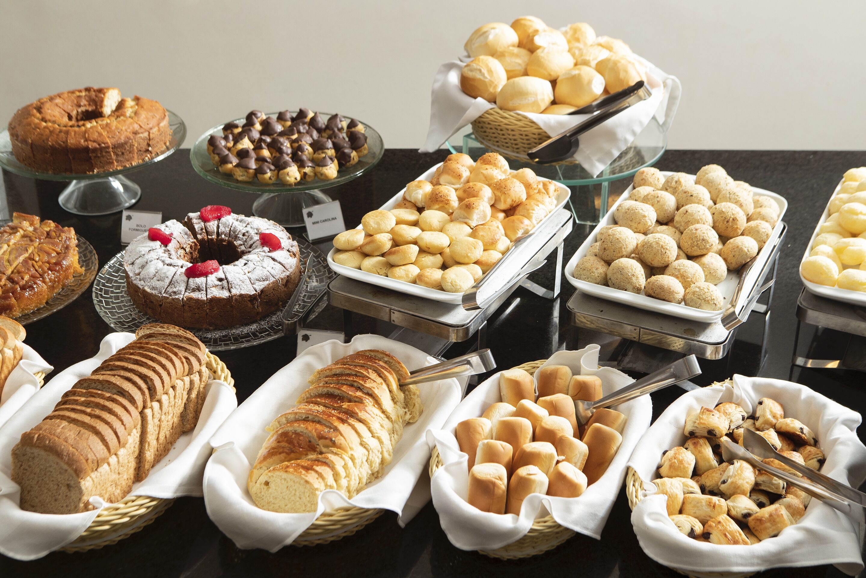 Un bufé con diversas opciones de panadería, incluyendo panes, pastelería y postres.