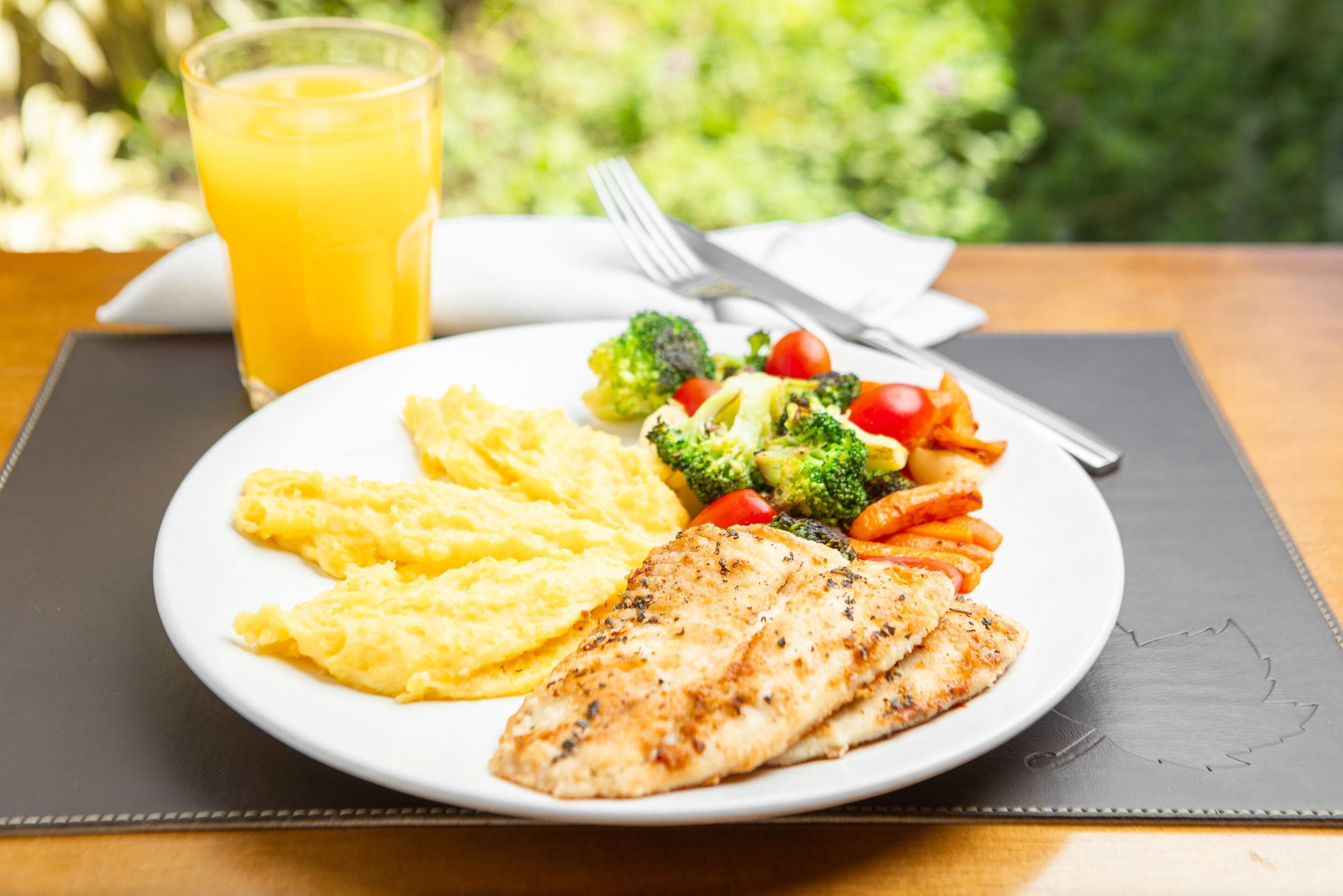 A plate of food with a glass of orange juice on a table.