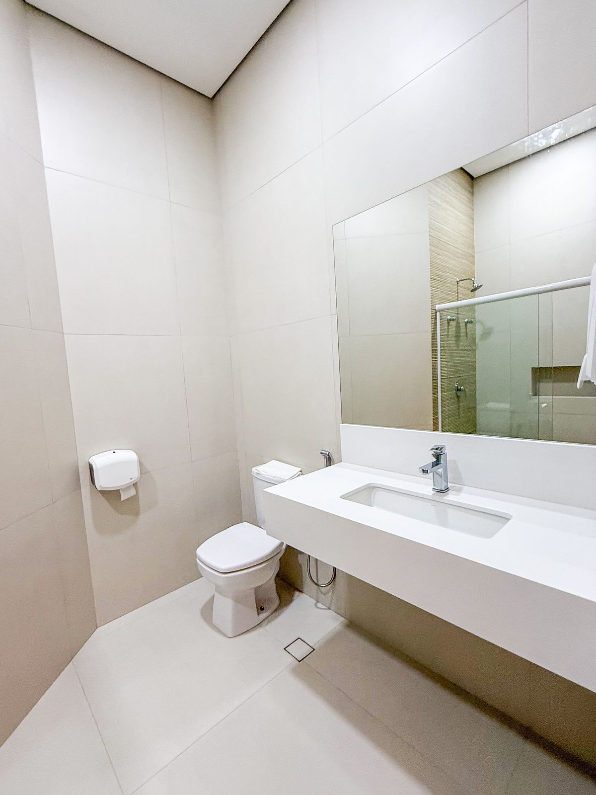 A modern bathroom with a white sink, mirror, and toilet.