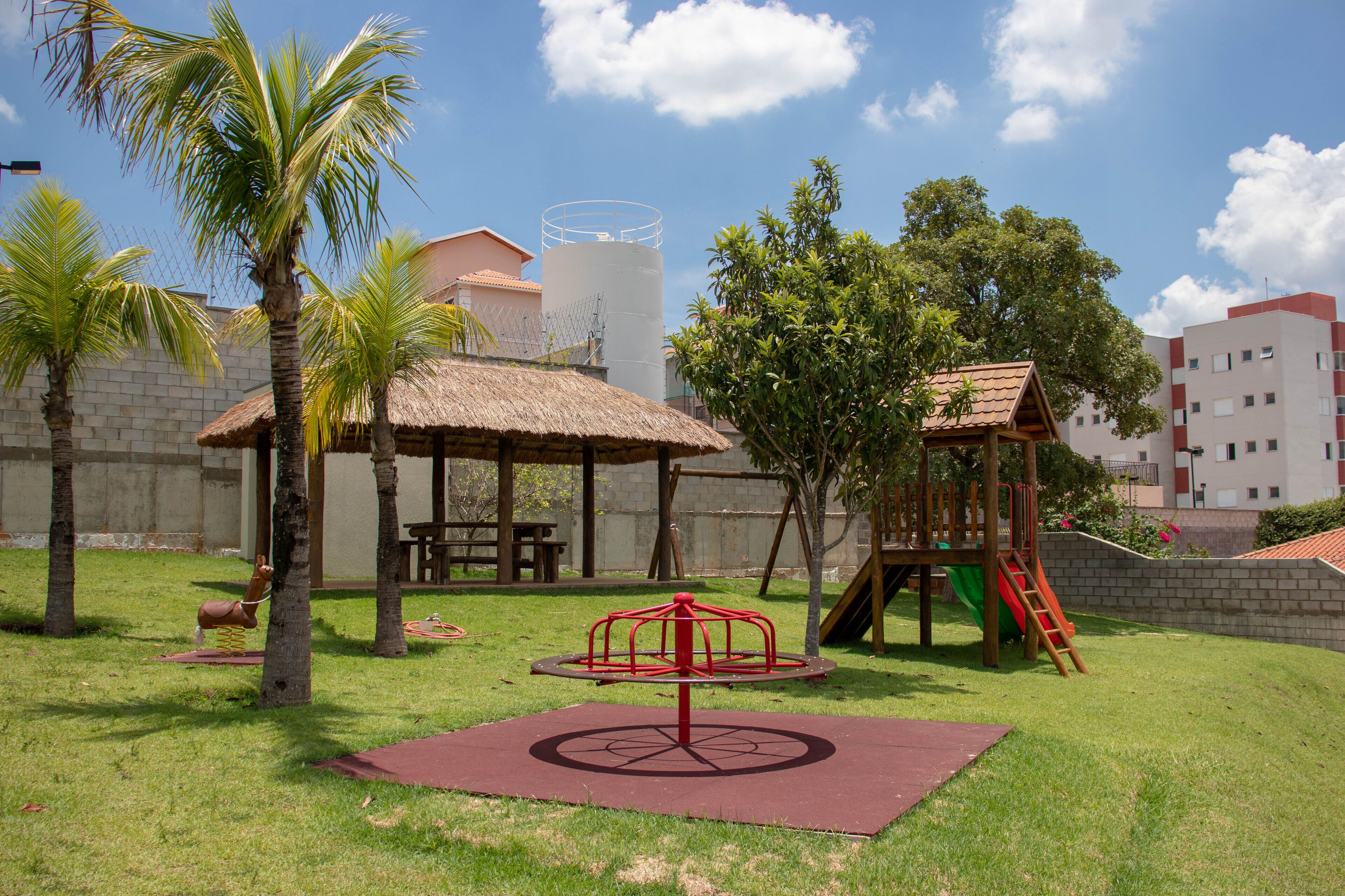 A playground with a swing set, a slide, and a red merry-go-round.