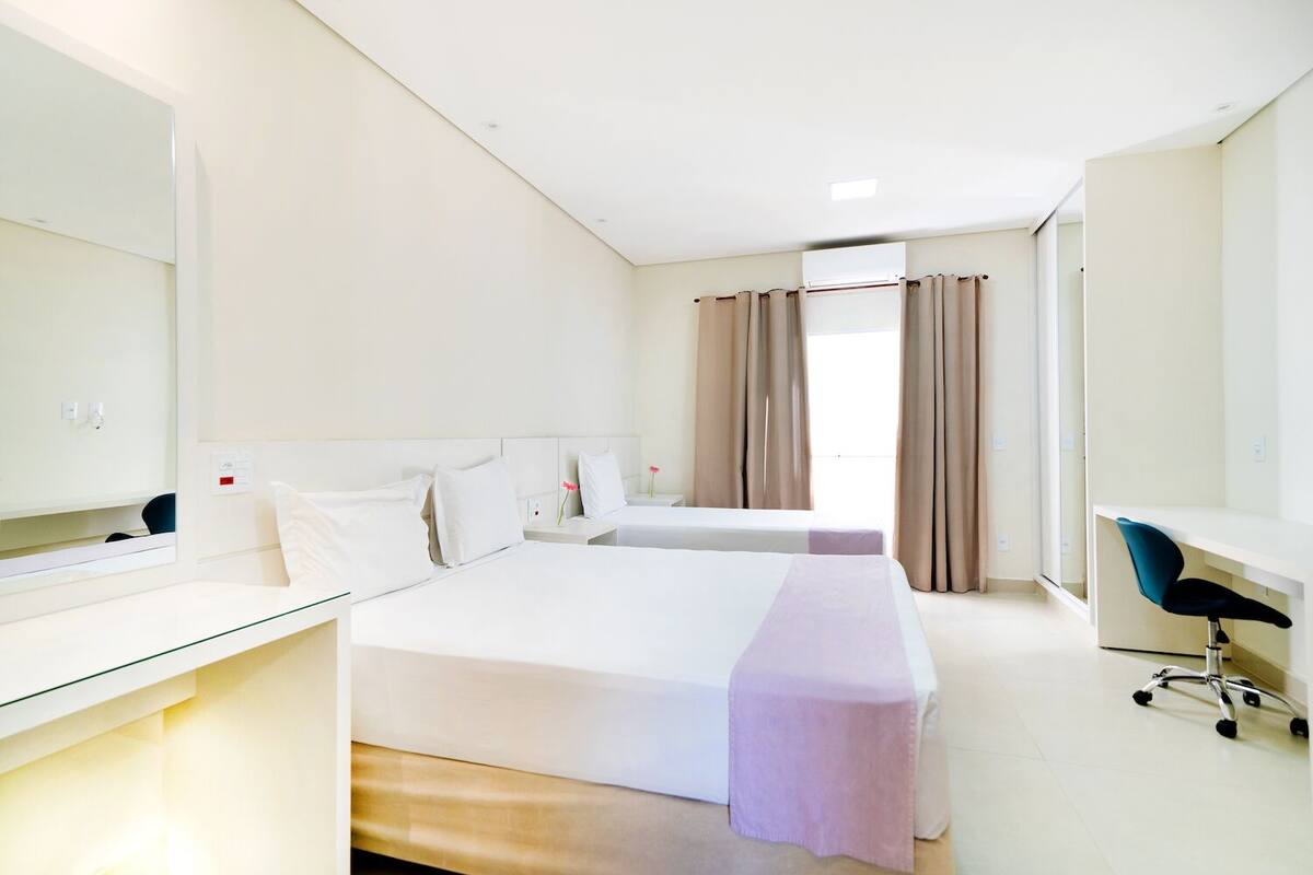 Una habitación de hotel con una cama grande, un escritorio, una silla y un espejo.