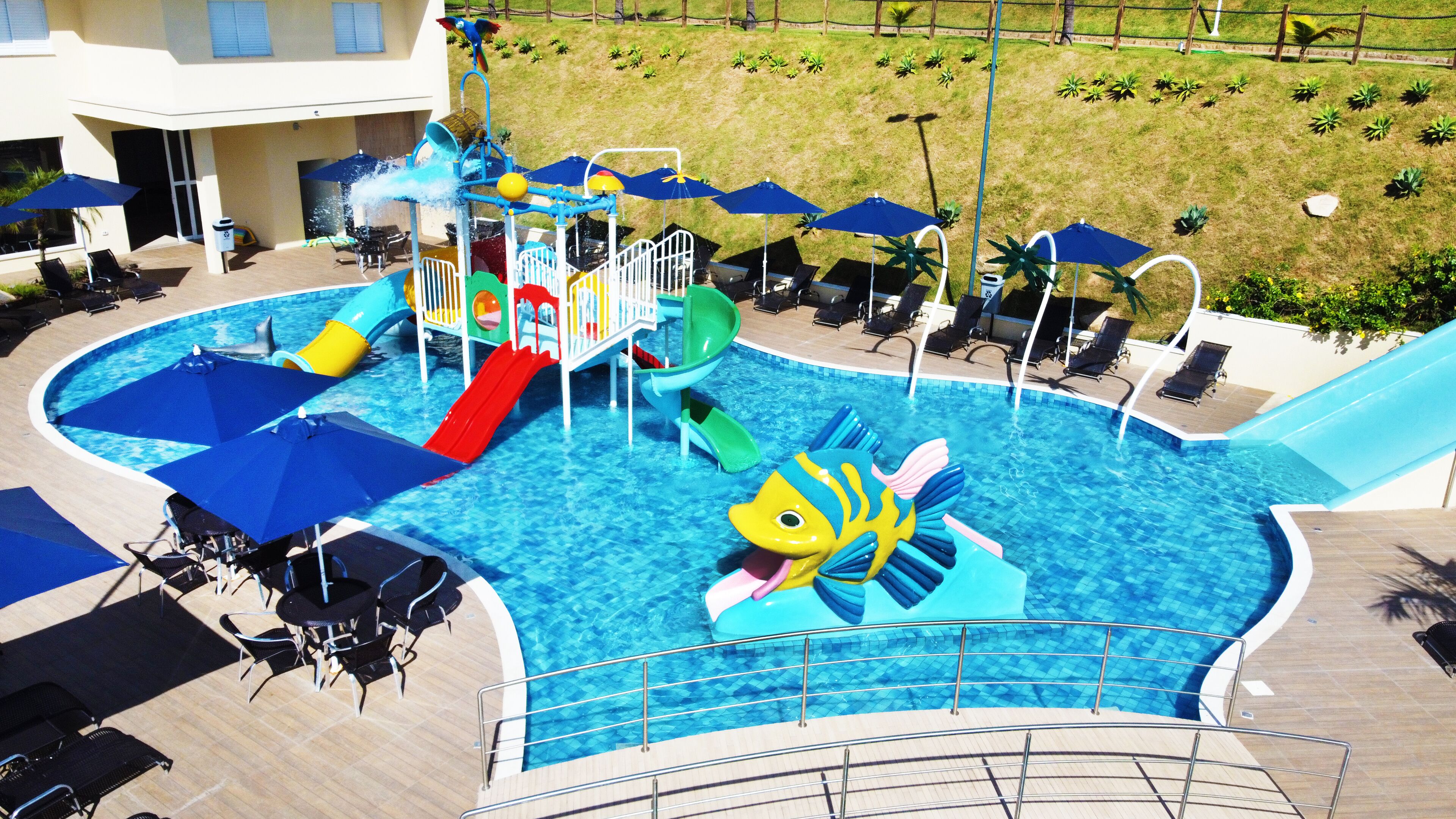 A pool area with a water slide, lounge chairs, and umbrellas.