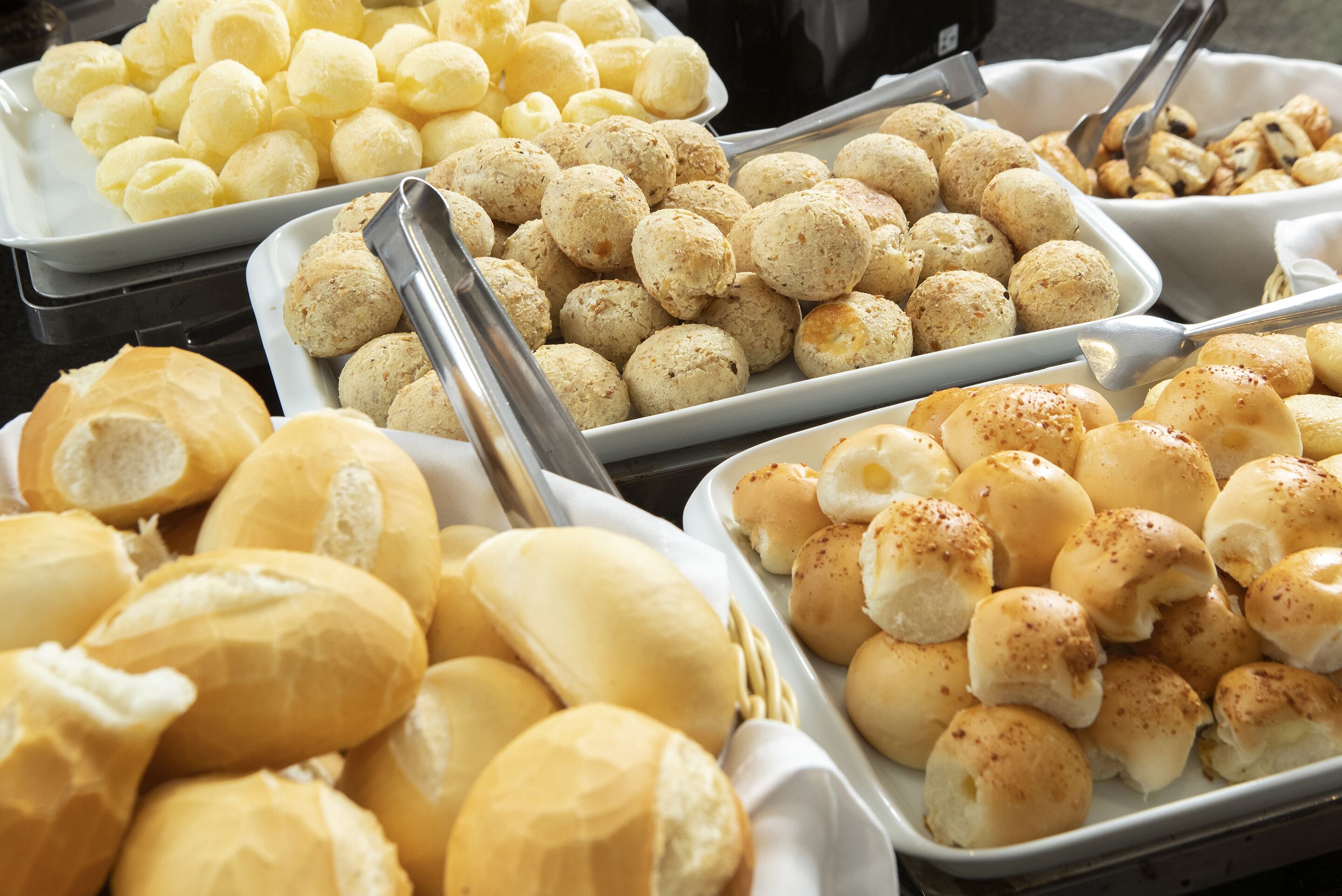 A buffet with various baked goods including bread rolls and pastries.