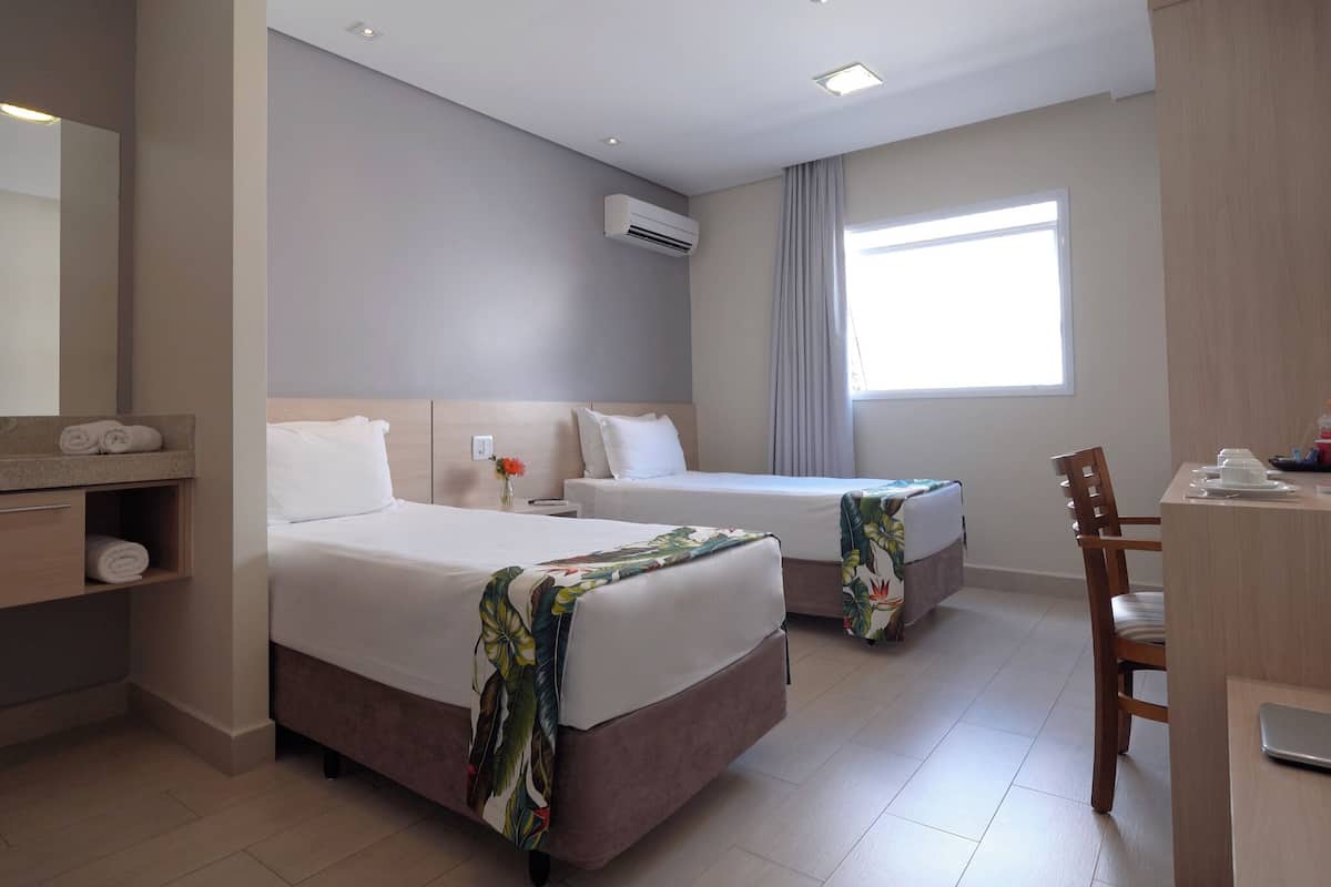 Une chambre d’hôtel avec deux lits, un bureau et une chaise.