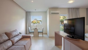 Een moderne woonkamer met een bank, een eettafel met stoelen, een flatscreen televisie en een airconditioning.