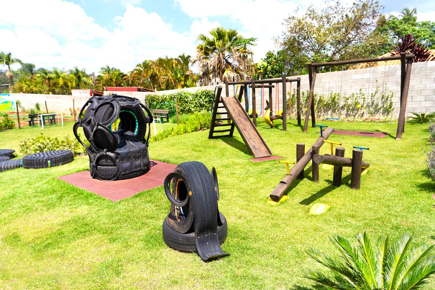 Un parque infantil con estructuras de neumáticos para escalar, un tobogán y un circuito de obstáculos de madera.