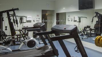 A gym with exercise equipment, a treadmill, and a mirrored wall.