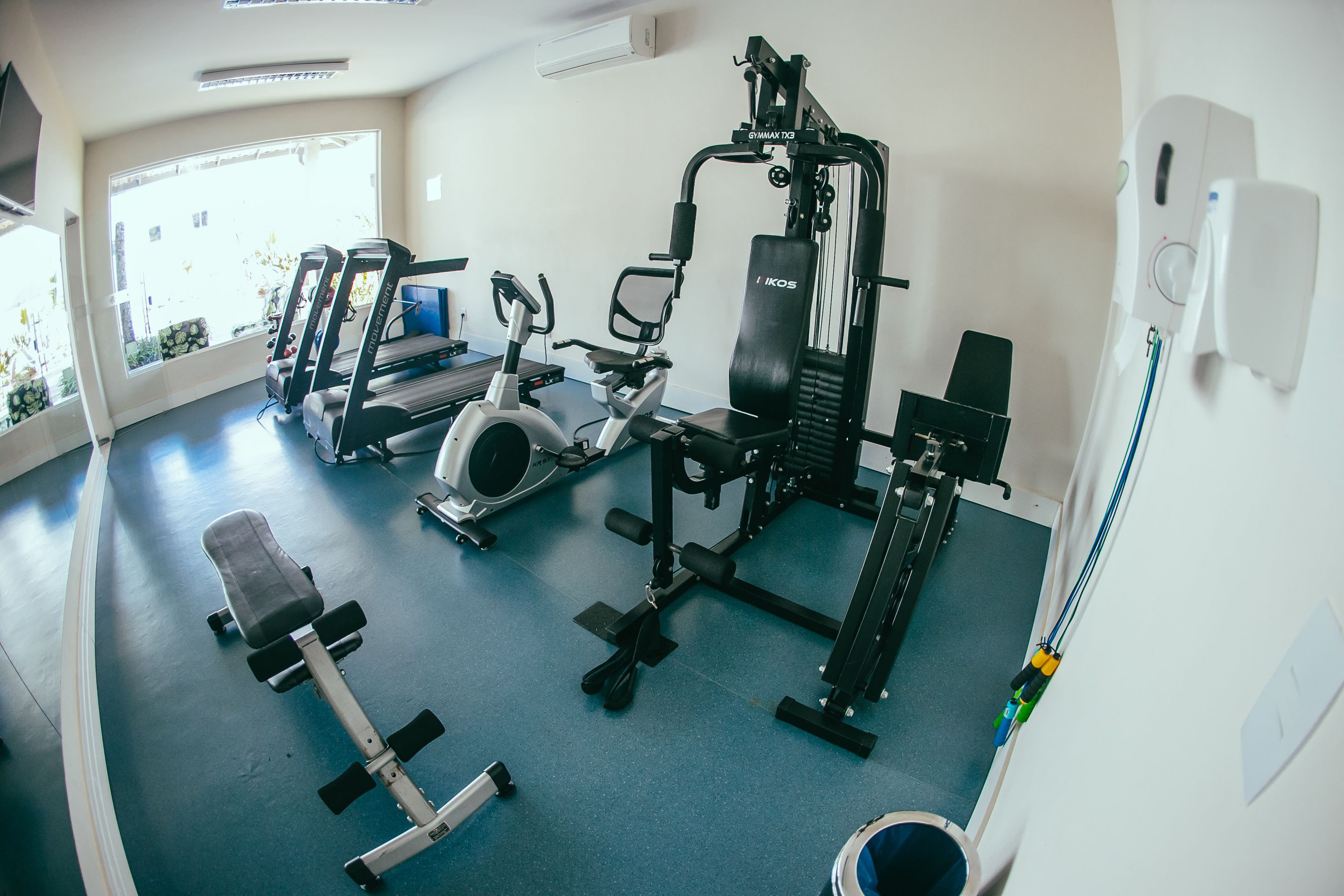 Un gimnasio con cintas de correr, elíptica, prensa de banca y máquinas de pesas.
