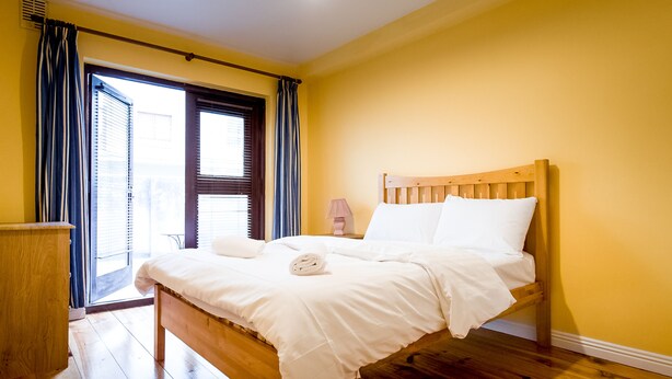 Ein Schlafzimmer mit einem hölzernen Bett, einem Nachttisch und einem Fenster mit Vorhängen.
