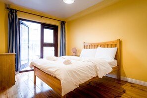 A bedroom with a wooden bed, a bedside table, and a window with curtains.