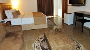 Una habitación de hotel con cama, escritorio, silla, televisor y refrigerador pequeño.