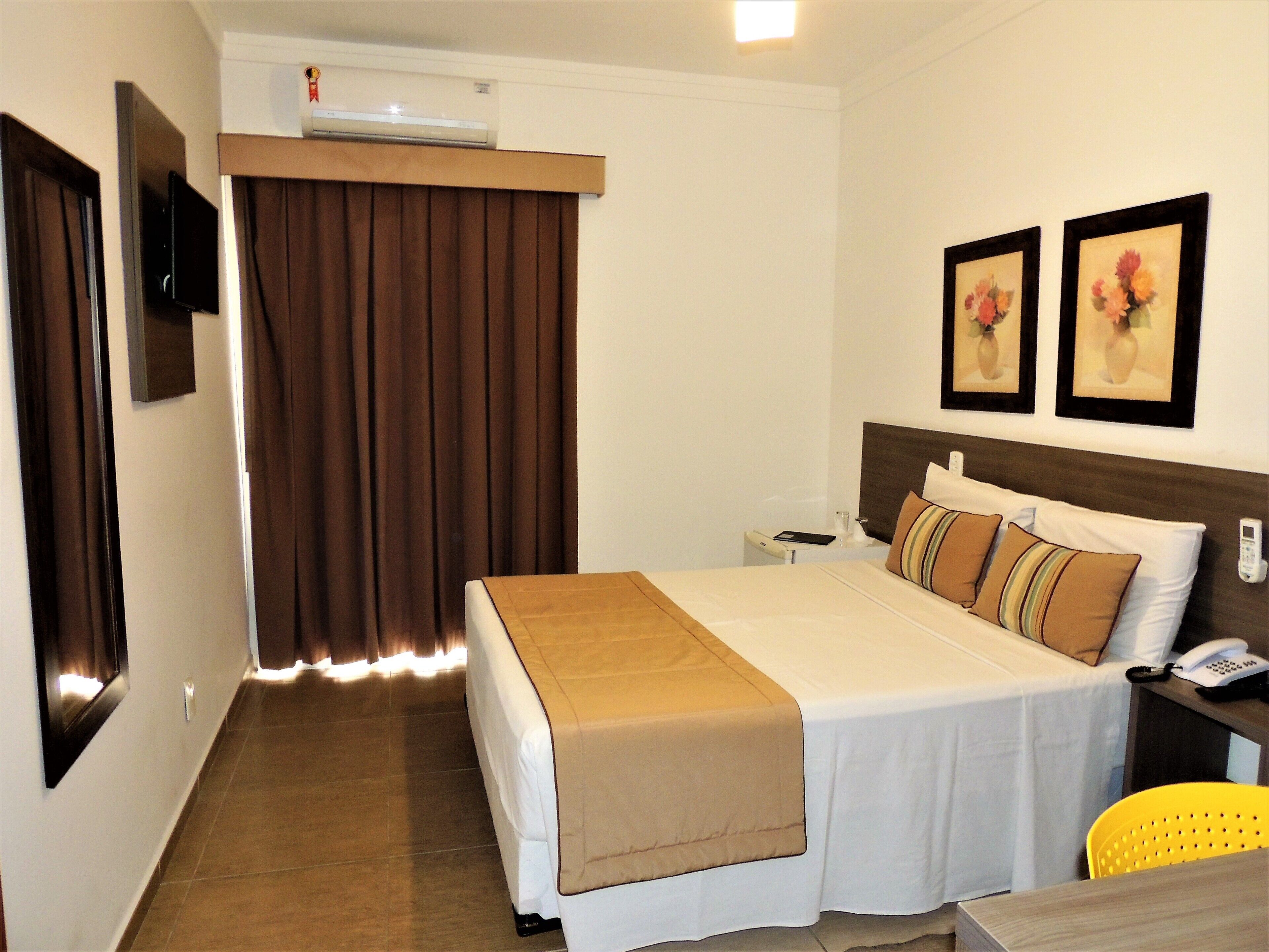 Una habitación de hotel con cama, mesita de noche y una silla.