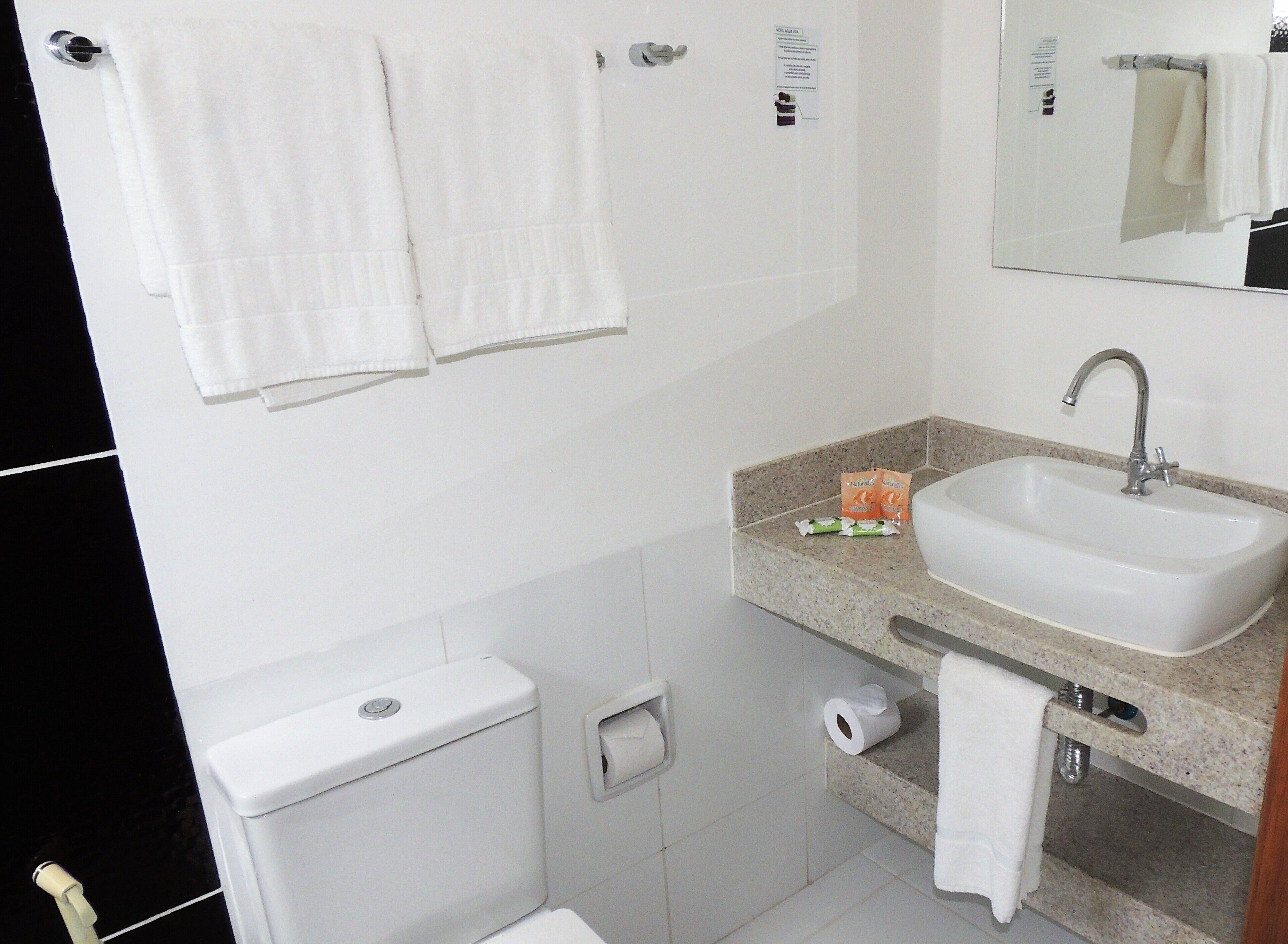 A bathroom with a sink, toilet, and two towels hanging on hooks.