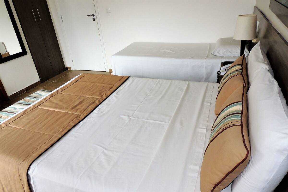 A hotel room with a bed, a nightstand, a lamp, and a wardrobe.