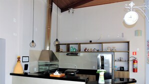 Una cocina moderna con una isla central, taburetes de bar, un refrigerador de acero inoxidable y una lámpara colgante.