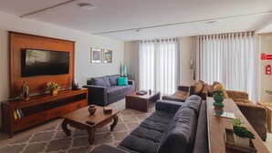 Una sala de estar moderna con un televisor de pantalla plana, sofás, una mesa de centro y un mueble de madera.