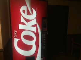 Una máquina expendedora con un llamativo logotipo de Coca-Cola y la palabra 'Enjoy'.