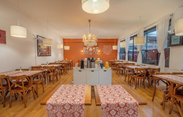 A dining area with wooden tables and benches, a chandelier, and a wall with various decorative items.