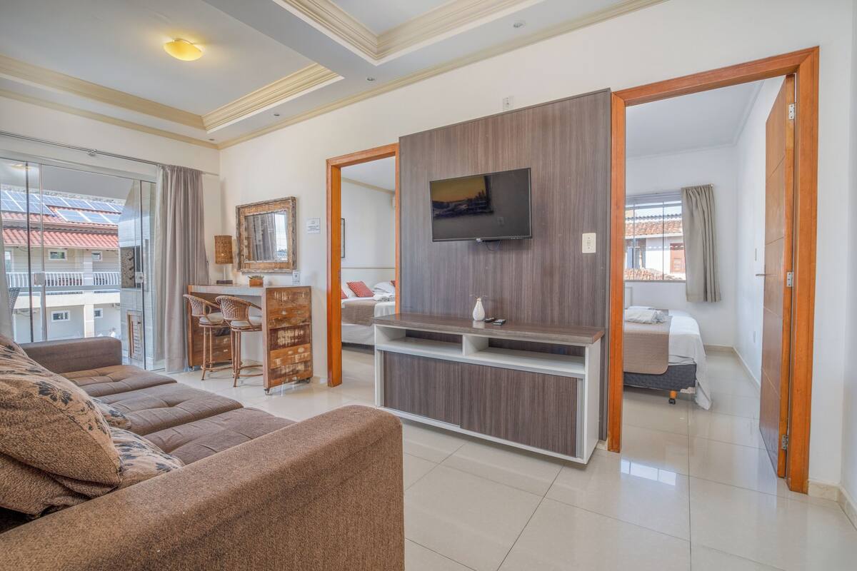 A modern living room with a sofa, TV, and a dining area with chairs.