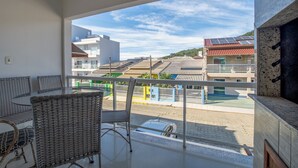 Ein Balkon mit Korbmöbeln, Blick auf Gebäude und einem klaren Himmel.