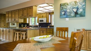 Una cocina con armarios de madera, un microondas y una mesa de comedor con un tazón de fruta.