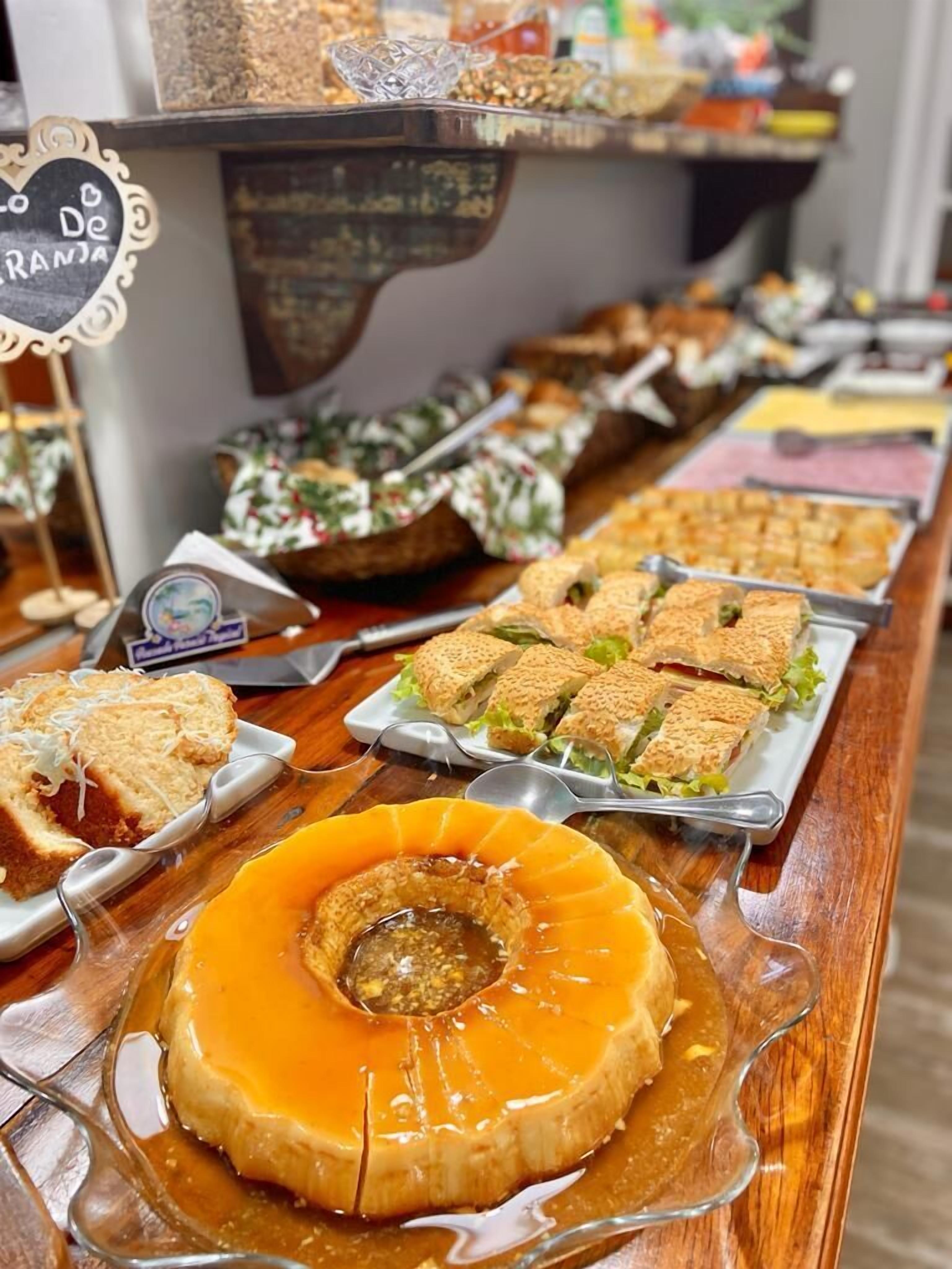 Een buffet met diverse gerechten, waaronder een caramel panna cotta, belegde broodjes en salades.