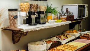 A buffet with various food items, including bread, pastries, and a coffee station. - Pousada Paraíso Tropical (Penha)