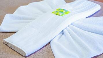 Una toalla blanca doblada con un emblema verde y amarillo sobre una superficie beige estampada.
