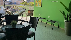A restaurant with a green wall, a logo, and a view of buildings through a window. - Pousada Paraíso Tropical (Penha)