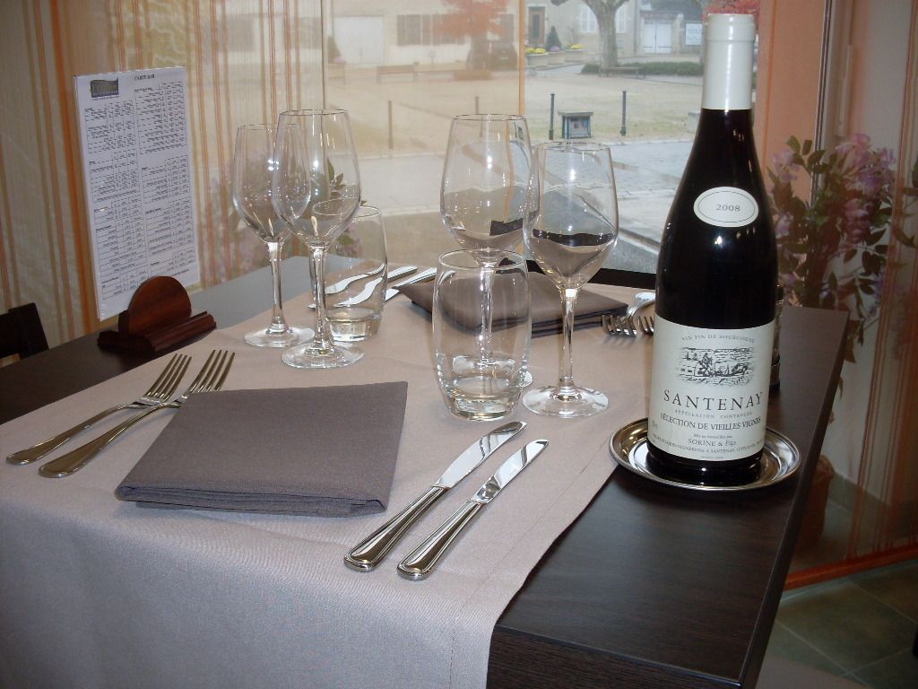 Une table mise pour le dîner, avec des verres à vin, des couverts et une bouteille de vin.