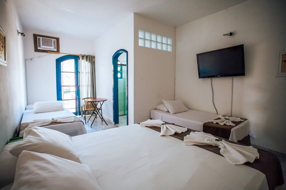 A hotel room with a large bed, a smaller bed, a TV, and a desk with a chair.