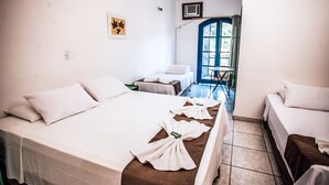 A hotel room with a large bed, two smaller beds, a chair, and a table. - Pousada Rafimar (Ilhabela)