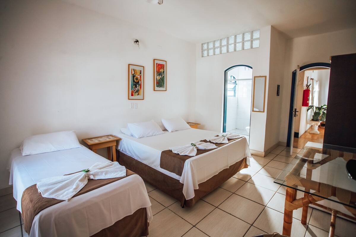 A hotel room with two beds, a glass table, and a mirror.