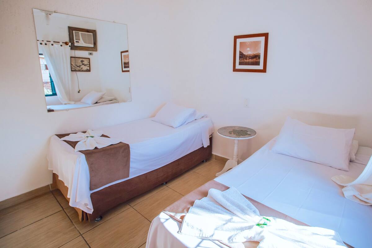 A hotel room with two beds, a round table, a mirror, and a framed picture on the wall.