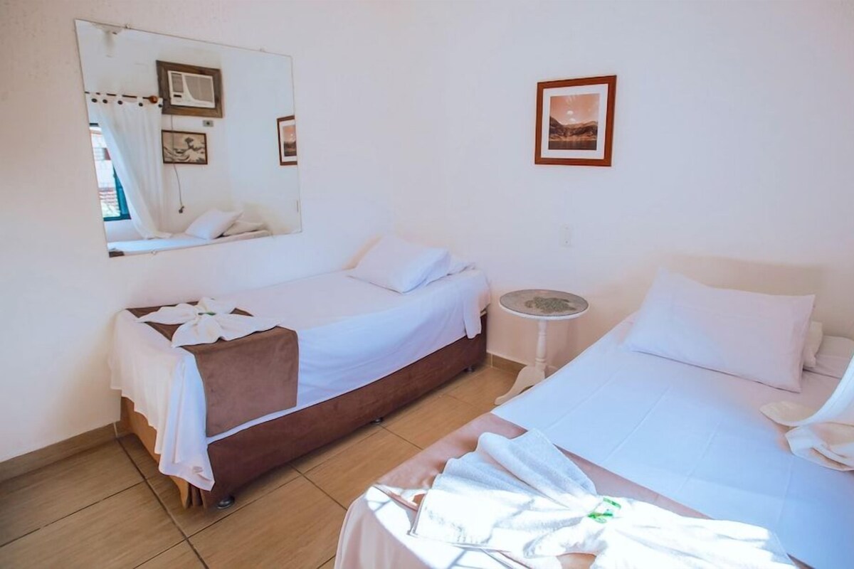 A hotel room with two beds, a small round table, a mirror, and a picture on the wall.