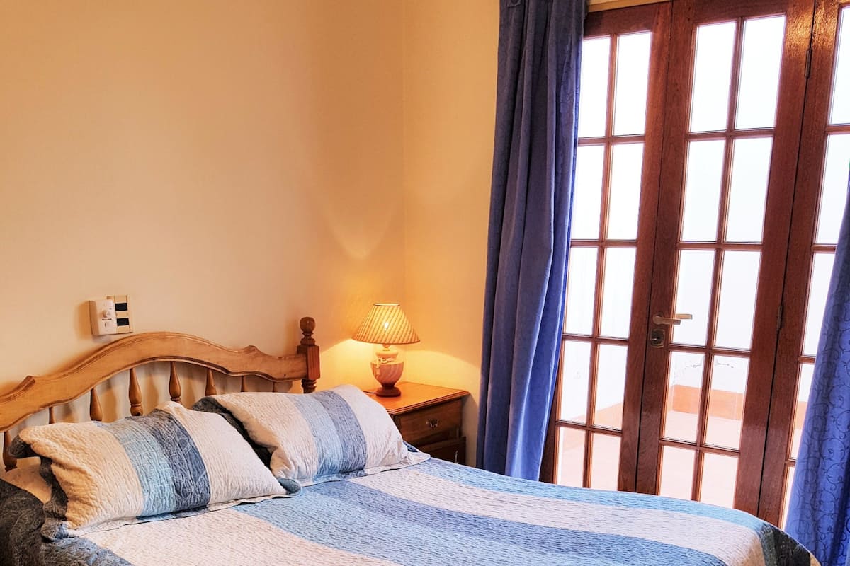 A bed with a striped blanket, a bedside lamp, and a wooden headboard.