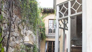 A narrow water feature with stone walls and a building with large windows and a balcony. - Posada de Los Leones (Antigua Guatemala)