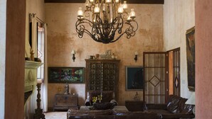 A room with a chandelier, a cabinet, a sofa, and a painting on the wall. - Posada de Los Leones (Antigua Guatemala)