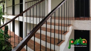 A staircase with a wooden handrail and black metal balusters, leading to a second-floor balcony with a white railing. - Hotel Posada Montaña del Quetzal (Salama)