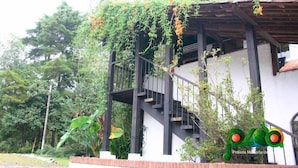 A building with a staircase leading to a covered area, surrounded by greenery. - Hotel Posada Montaña del Quetzal (Salama)