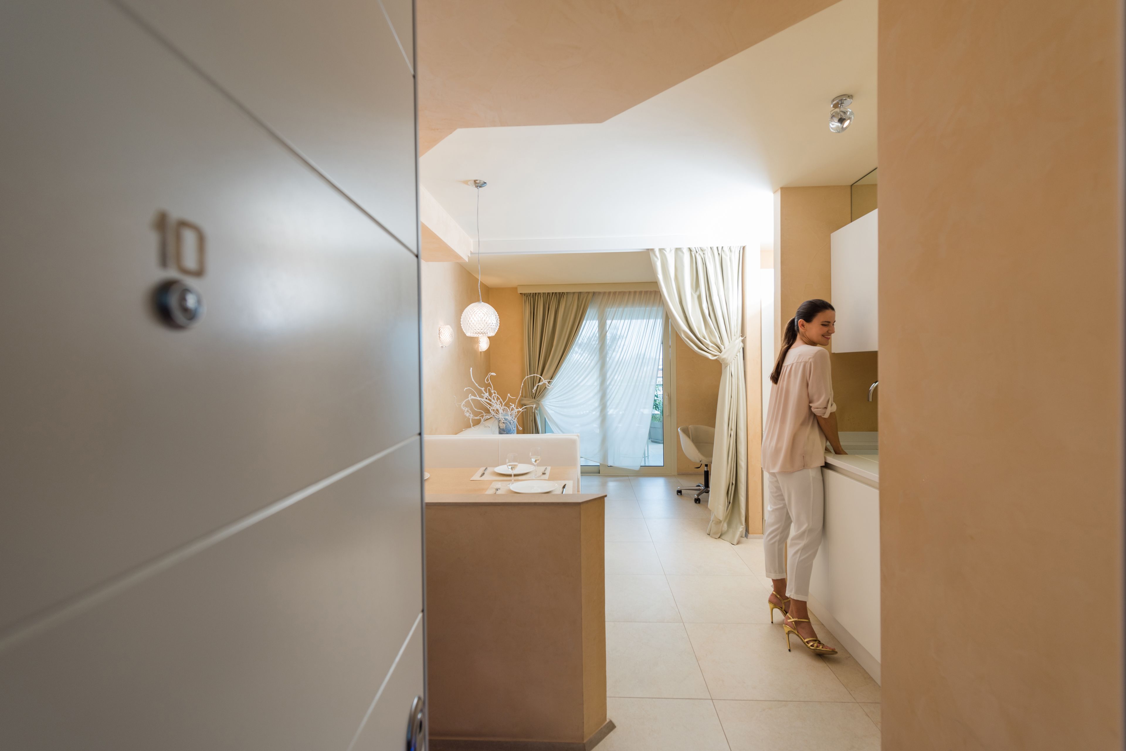 A modern hotel room with a large wardrobe, a vanity with a mirror, and a dining area with a table set for two.
