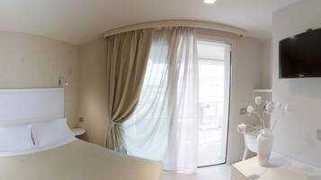 Ein modernes Hotelzimmer mit Bett, Nachttisch und Wandfernseher.