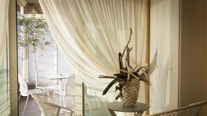 A room with a glass table, wicker chairs, and a decorative vase with natural elements. - Residence Spa Mirabel (Grado)