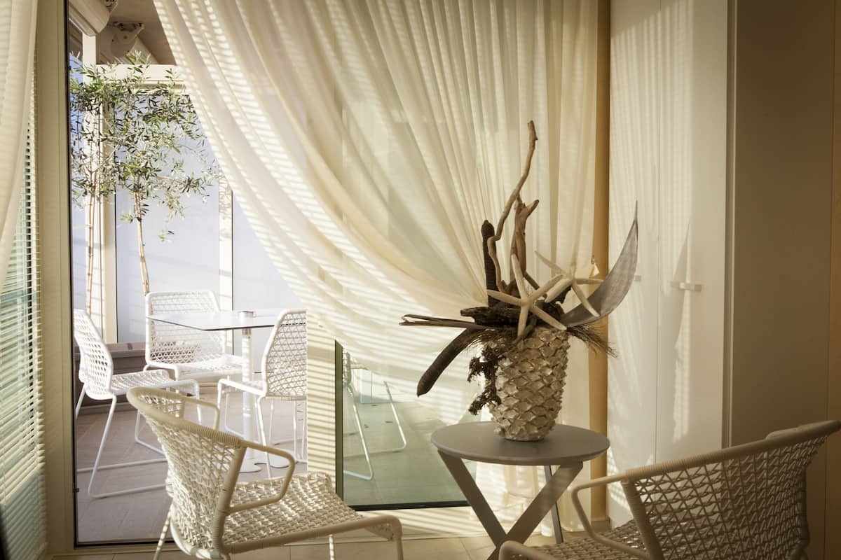 Une pièce avec une table en verre, des chaises en osier et un vase décoratif agrémenté d’éléments naturels.