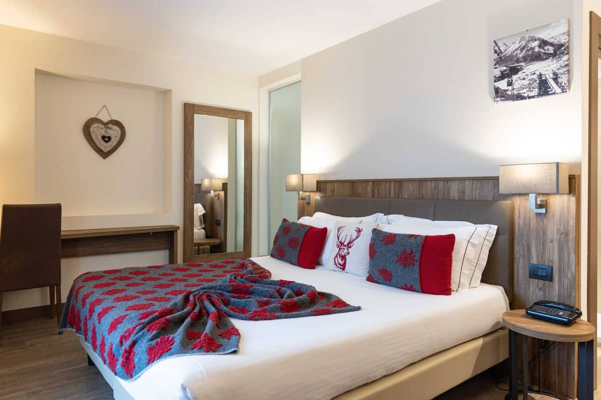 A hotel room with a bed, bedside table, and a mirror.