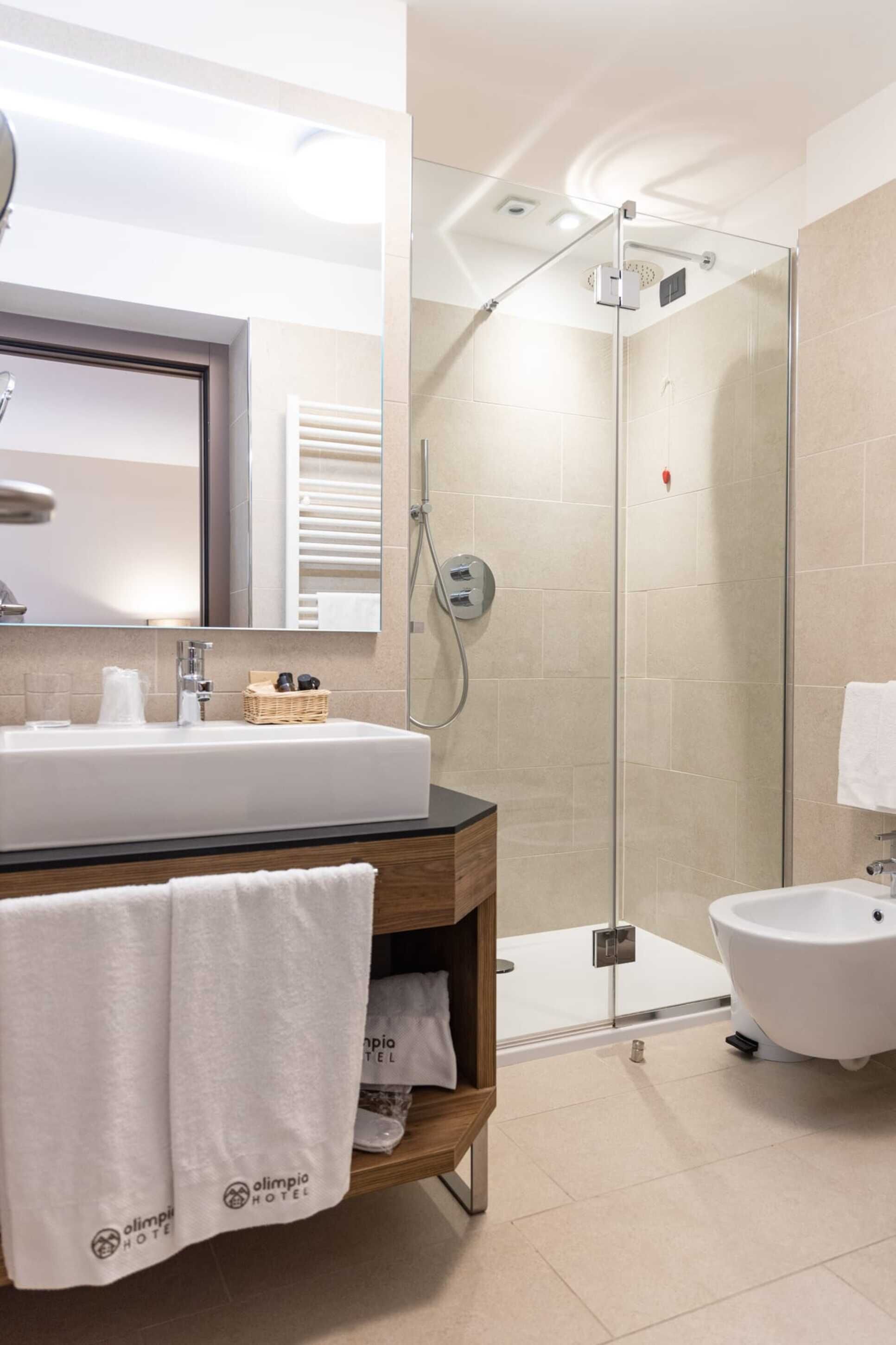 Un baño moderno con un lavamanos grande, una cabina de ducha de vidrio y un bidé.