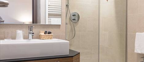Un baño moderno con un lavamanos grande, una cabina de ducha de vidrio y un bidé.