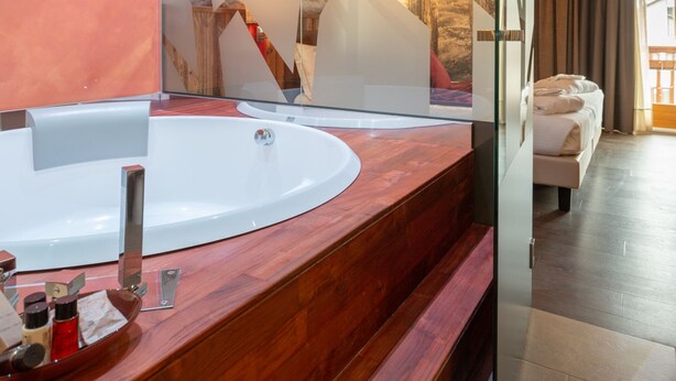 A modern bathroom with a wooden vanity, a large mirror, and a bathtub. - Olimpia Hotel (Bormio)
